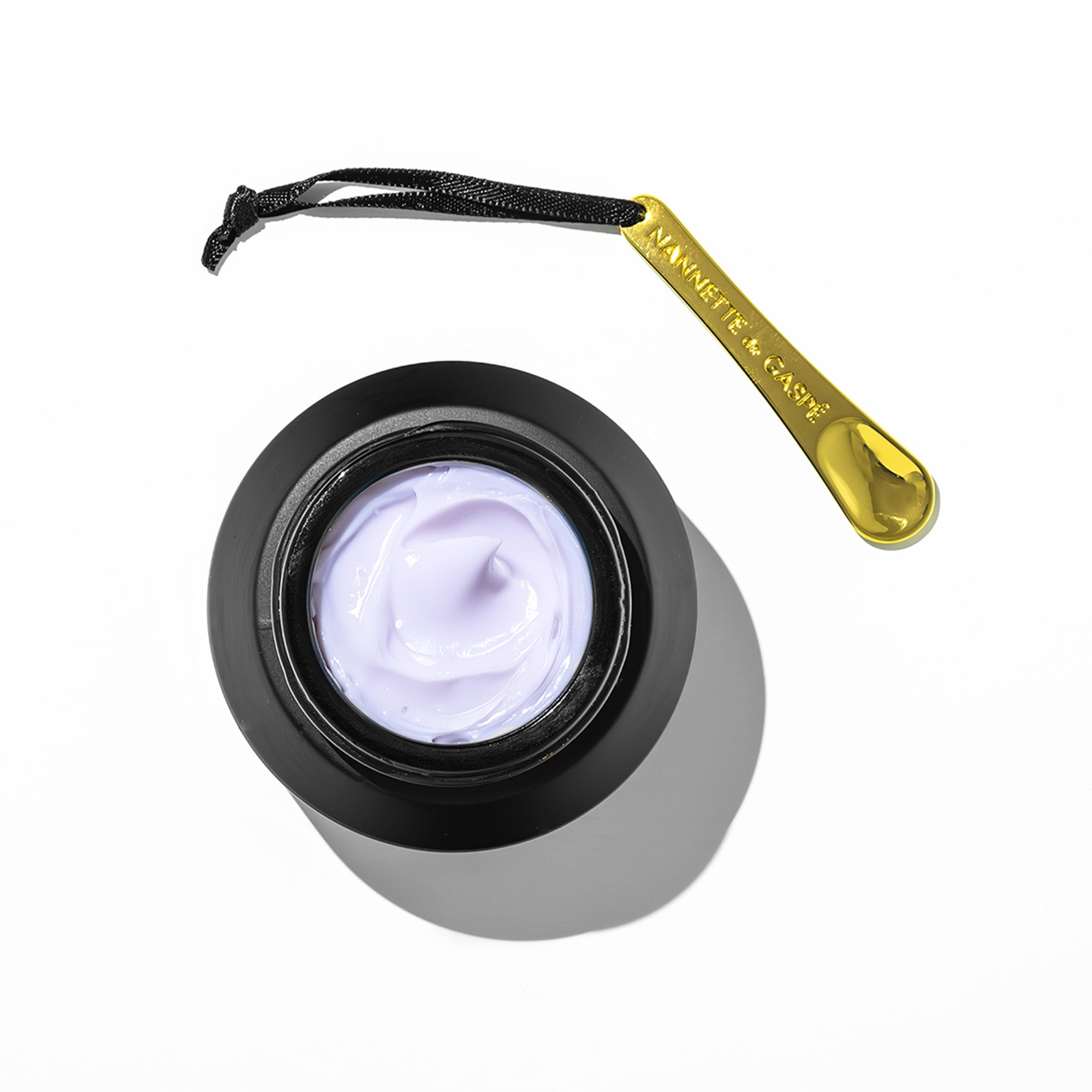 Baume Noir Face cream open jar with gold spatula showing rich lavender texture