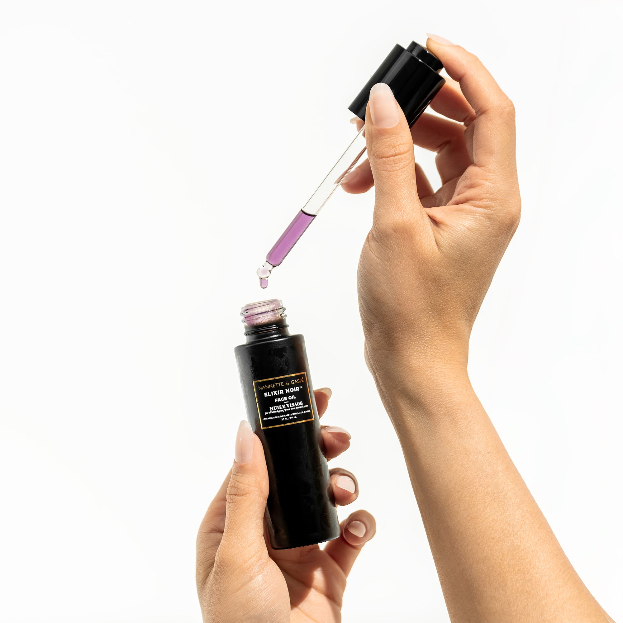 Applying Elixir Noir Face Oil—dropper over hand for dewy, hydrated, radiant skin finish